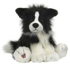 a black and white dog stuffed animal sitting on the ground with its paw up to it's face