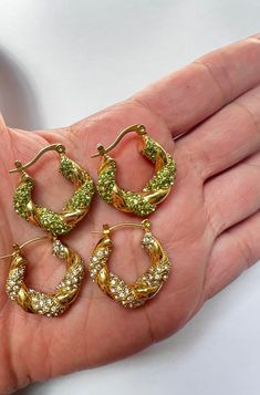 Our 18K Gold CZ Hoop Twist Earrings are a beautiful addition to your everyday wear or for a night out!  Comes in 2 colors: Light green and white Chunky small braid hoops, diamond thick hoops, 18K hoop earrings. Details: Diameter: 2.4 cm Green/White Cubic Zirconia High Quality Gold Plated Tarnish Resistant J E W E L R Y . C A R E We stand behind the quality of our jewelry however to ensure the longevity of your gold, we recommend removing it while bathing, washing hands, applying lotions, perfume Green Small Hoop Earrings Tarnish Resistant, Small Hoop Green Earrings Tarnish Resistant, Green Tarnish Resistant Small Hoop Earrings, Small Hoop Green Tarnish-resistant Earrings, Trendy Green Huggie Jewelry, Trendy Green Huggie Hoop Earrings, Green Hypoallergenic Small Hoop Huggie Earrings, Hypoallergenic Green Small Hoop Huggie Earrings, Hypoallergenic Small Green Huggie Earrings