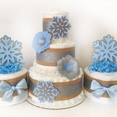 three tiered cake decorated with snowflakes and blue flowers on each layer, sitting side by side