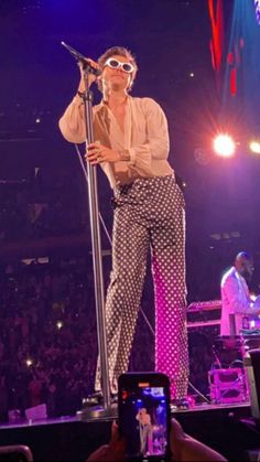 a man standing on top of a stage holding a microphone in front of an audience