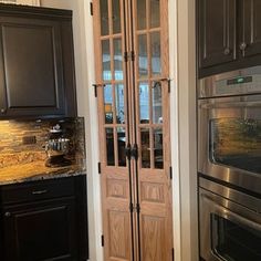 a kitchen with black cabinets and stainless steel stove top oven in the corner next to an open pantry door