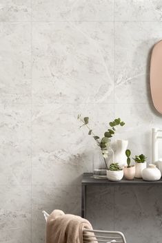 a bathroom with marble walls and flooring, including a mirror on the wall next to a chair