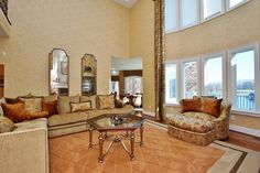 a living room with couches, chairs and mirrors on the wall in front of windows