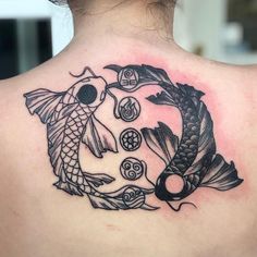 the back of a woman's shoulder with a tattoo design on it, depicting two koi fish in a circle