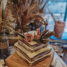 there is a layered cake with flowers and feathers on the top, sitting on a table