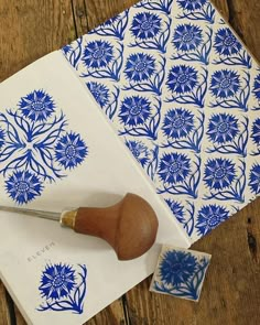 blue and white paper with flower designs on it next to a stamper that has a wooden handle