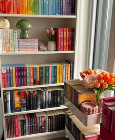 there are many books on the shelves and vases in front of them with flowers