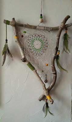 a piece of art made out of branches with beads and feathers hanging from it's sides