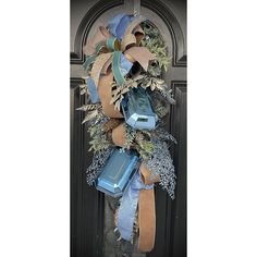 a wreath on the front door is decorated with blue and brown ribbons, leaves, and boxes