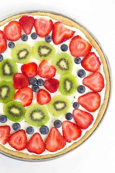 a pie topped with sliced kiwis, strawberries and blueberries on top