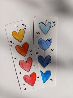 two tags with hearts drawn on them sitting next to each other