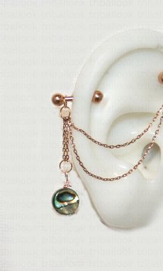 an earring with chains attached to it sitting on top of a white plate next to a pair of earrings