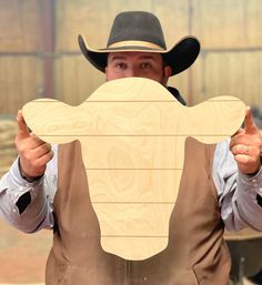 a man in a cowboy hat holding up a wooden board