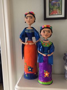 two wooden dolls sitting on top of a shelf