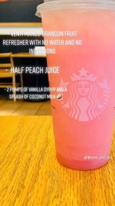 a pink starbucks cup sitting on top of a wooden table