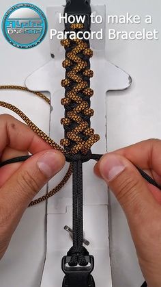 someone is making a paracord bracelet out of two pieces of black and gold string