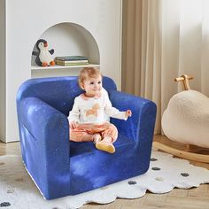 a baby sitting on a blue chair in a room with white walls and flooring