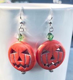 two pumpkins with faces carved into them sitting on a white cup next to each other