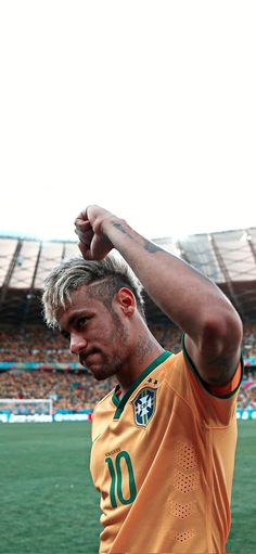 a man with his arm up in the air at a soccer game, wearing an orange and green uniform