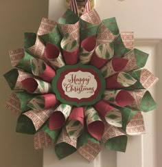 a christmas wreath hanging on the front door decorated with red, green and white paper