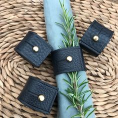 four pieces of black leather sitting on top of a blue napkin next to a sprig of rosemary