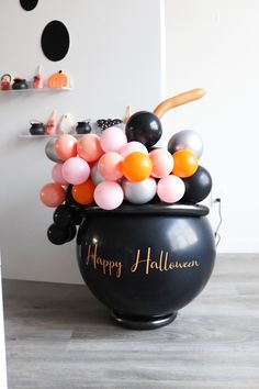 a large black pot filled with balloons on top of a wooden floor