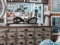 a tv sitting on top of a wooden dresser next to a vase filled with flowers