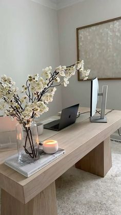 there is a vase with flowers and candles on the table in front of a laptop