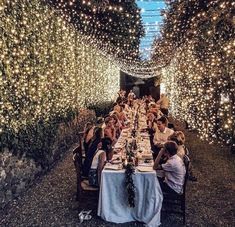 a group of people sitting at a long table in the middle of a tunnel filled with lights