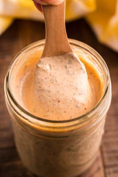 a wooden spoon in a jar filled with dressing