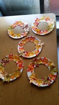 four plates with leaves on them sitting on top of a table next to a window