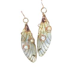 Ethereal Fairy Wing Earrings Delicate and magical are the only way to describe these pretty Cicada wing earrings. A 2 inch long wing with a drop of 2.25 inches,they dangle so lightly being made from translucent plastic.  They are so light you won't even know you are wearing them!  A touch of sparkle is added to the wing with  holographic glitter that gives a special touch of magic to the fairy earrings. Two crystals that match the color of the wing dance upon copper wire swirls th Cute Fairy Earrings, Cheap Whimsical Metal Jewelry, Whimsical Cheap Metal Jewelry, Fantasy Accessories Earrings, Cicada Wing Earrings, Fae Wings, Earrings Wing, Wire Swirls, Fairy Wing Earrings