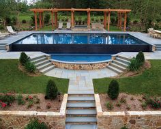 an outdoor swimming pool with steps leading up to it and landscaping around the pool area