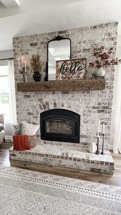 a living room with a brick fireplace and white rugs on the hardwood flooring