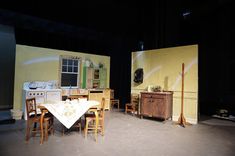 an empty stage with chairs, table and stove in it's centerpieces