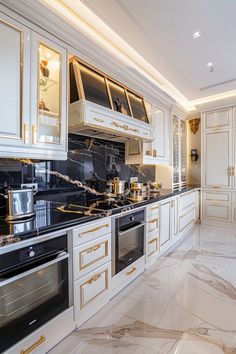 a kitchen with marble counter tops and white cabinets, along with gold trimmings