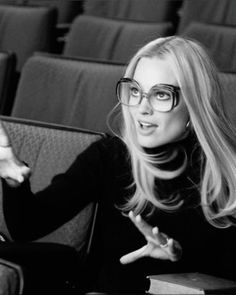 a woman with glasses sitting in an empty theater