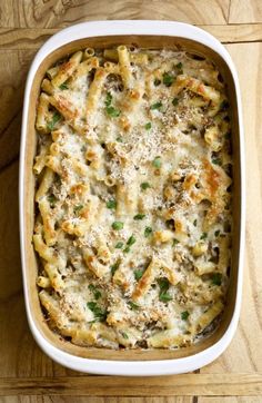 a casserole dish filled with pasta and meat covered in cheese, green onions and parmesan