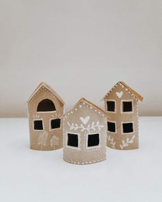 three small houses made out of cardboard and decorated with hearts on the front, one is brown