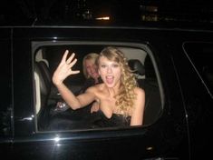 a woman sitting in the back seat of a car waving