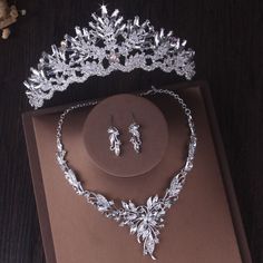 a tiara and earring set on top of a brown box next to a flower