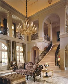 a fancy living room with chandelier and couches in it's center