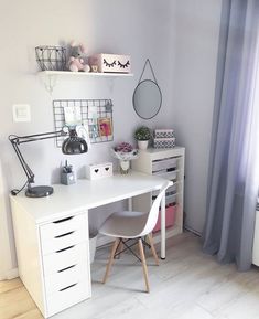 a white desk and chair in a small room with curtains on the window sill