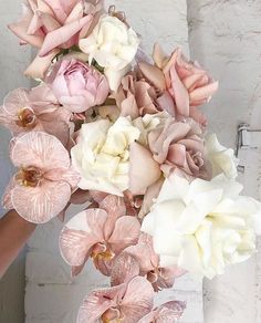 a bouquet of pink and white flowers is being held by a woman's hand