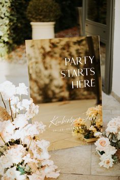 a sign that says party starts here next to flowers