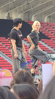 two people standing on top of a stage in front of an empty bleachers