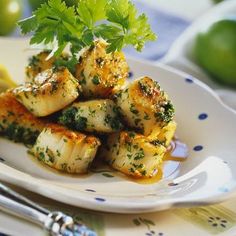 scallops covered in sauce and garnished with parsley on a white plate