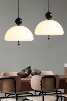 three lamps hanging from the ceiling in a room with beige chairs and black shoes on them