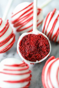 red velvet cake pops with white chocolate drizzled on top and candy in the background