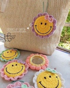 crocheted smiley face coasters on a table next to a handbag and purse